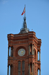 Clock tower of red city hall in Berlin near Alexanderplatz under blue sky
