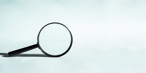 A black magnifying glass on a blue background, concept of search, research, looking for something....