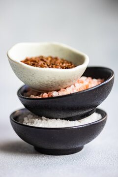 Stack of bowls filled with flax seeds, pink Himalayan salt and rock salt