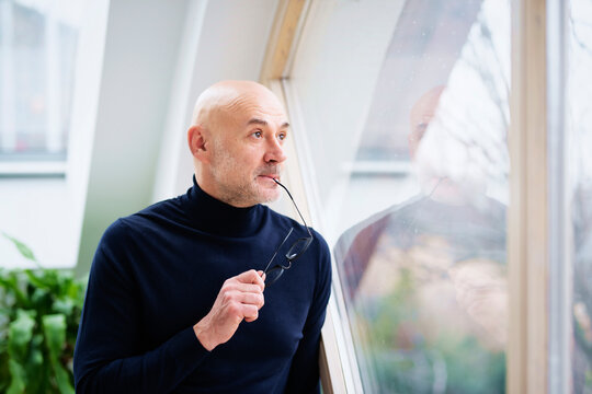Man looking thoughtfully while standing at the window and looking out