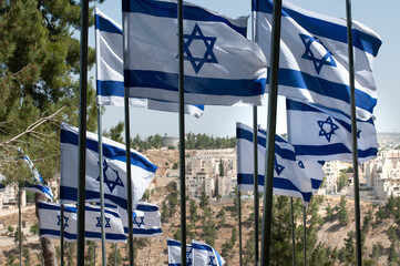 Multiple, large, blue and white flags of the State of Israel rippling in the wind during the...