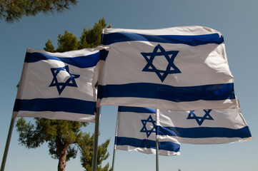 Multiple, large, blue and white flags of the State of Israel rippling in the wind during the...