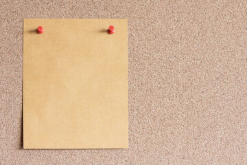 Blank Brown paper note with pin on corkboard. With copy space for ideas, reminders, appointments,...