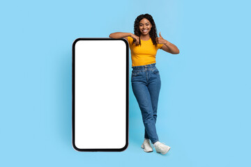 Positive african american lady posing with smartphone with blank screen