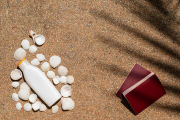 the layout is a white bottle for sunscreen with shells, passports, frangipani flower and shade from a palm tree. Travel flat lay. Cosmetic presentation