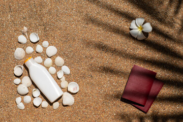 the layout is a white bottle for sunscreen with shells, passports, frangipani flower and shade from a palm tree. Travel flat lay. Cosmetic presentation