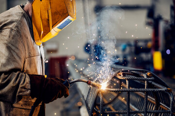 A heavy industry metal worker welding armature in metal factory.