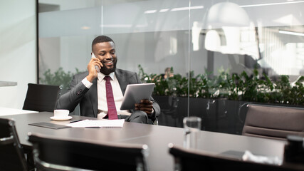 Happy black entrepreneur using digital tablet, talking on phone