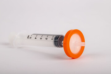 syringe standing on white background with needle tip filter attached.