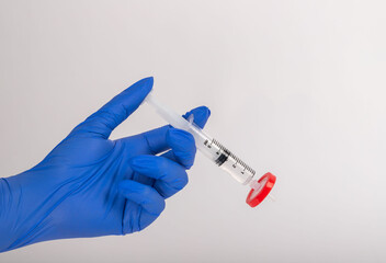 Scientist holding a needle conducts an experiment in the laboratory. He is wearing blue gloves.
