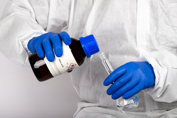 Scientist holding nitric acid in laboratory environment. It shows the way of use before the experiment. He has blue gloves on his hands