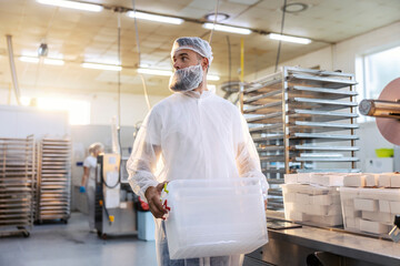 A food factory worker is relocating plastic containers. 