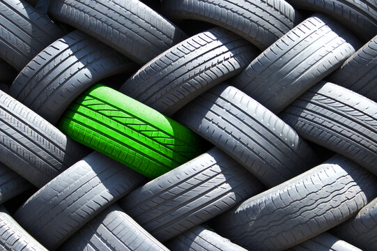 Single green tyre in a stack of tires.