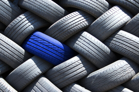 Single blue tyre in a stack of tires. 