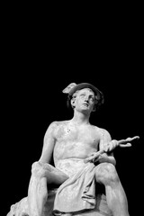 Black and white image of an ancient statue of antique god of commerce, business, merchants and travelers Hermes (Mercury) isolated on black background.