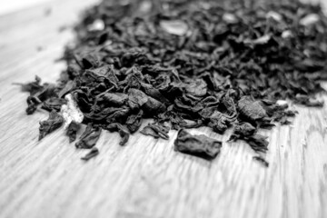 Dry black tea isolated on wooden board with blur effect in black and white.