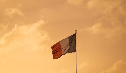 The national flag of France winding against sunset sky