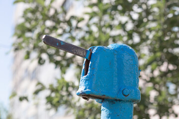 A blue street water pump in a modern city against the backdrop of a nine-story Soviet building