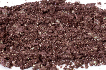 Scattered dark brown eye shadow isolated on a white background