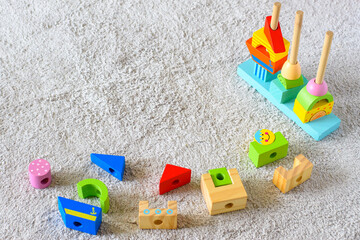 Colorful wooden pyramid with geometric details on a white cotton carpet. Eco friendly, plastic free toys for toddler. Space for text