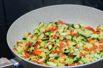 Zucchini and red peppers in pieces in a pan