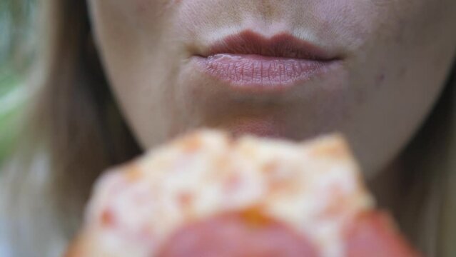 Young woman outdoors eating italian pizza. Close up bites a piece of pizza