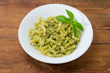Spiral pasta with sauce pesto, decorated with fresh basil twig