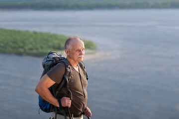 Staycations, hyper-local travel, family outing, getaway, natural environment. Senior man with backpack hiking in outdoor. Digital detox. 