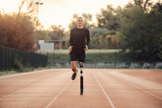 A handicapped runner with prosthetic leg running at the stadium on running track.