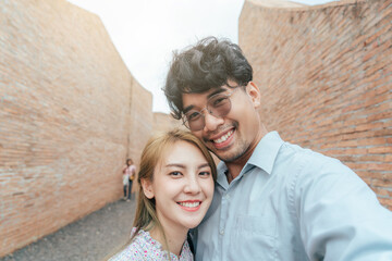 Happy Asian couple traveler take a photo selfie in love and travel coliseum architecture at Surin...