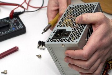 the master repairs the computer's power supply unit unscrews the screw with a screwdriver