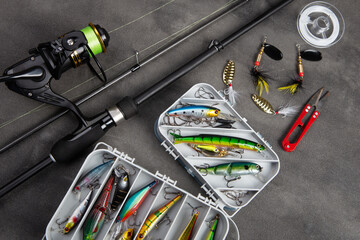 Fishing tackle - fishing spinning rod, hooks and lures on gray background. Active hobby recreation...