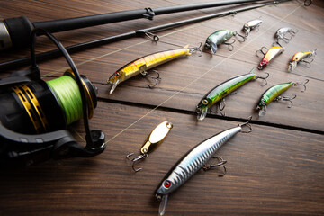 Fishing tackle - fishing spinning rod, hooks and lures on wooden background. Active hobby...