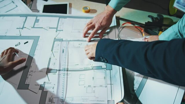 Top view hands group engineers and architects men discuss the blueprint. Design building construction in the evening light. Close up. Slow motion