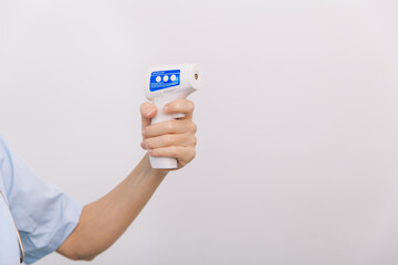 Temperature measurement gun in doctor hands. Close-up shot of doctor wearing protective surgical mask ready to use infrared isometric thermometer gun to check body temperature for virus symptoms.