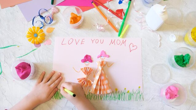 Child making homemade greeting card from paper and clay, plasticine as gift for Mothers day, Birthday or Valentines day . Arts  crafts concept.
