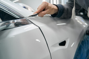 Skilled worker removing extra PPF coating from vehicle