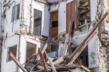 building in ruin with a collapsed wall and visible damaged apartments