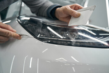 Experienced detailer removing excess clear protection film from headlight
