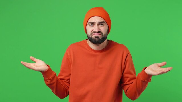 Fun confused shy shamed bewildered sad young brunet man 20s years old wears red shirt hat look camera spreading hands say oops ouch oh omg i am so sorry isolated on plain light green background studio