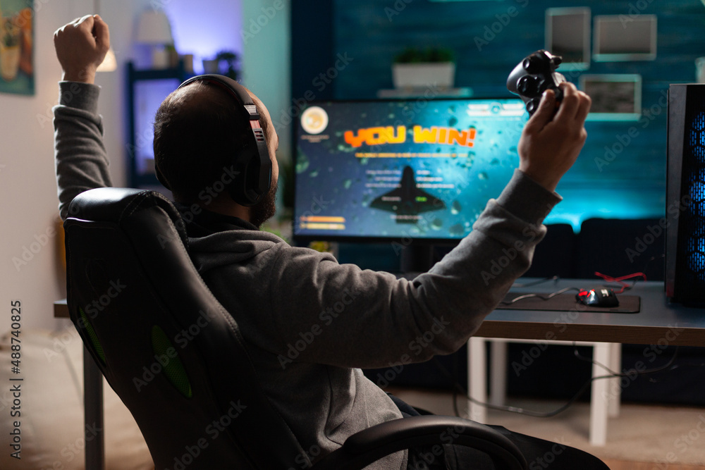 Poster person playing video games with controller and winning in front of computer. gamer using joystick an