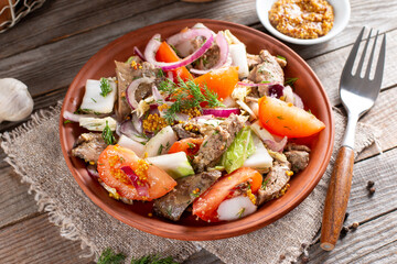 Warm salad with chicken liver, tomatoes and salad mix in a plate
