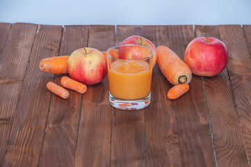 Carrot-apple puree in a glass cup on a natural wood table. Homemade diet food from natural carrots and apples.