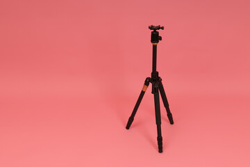 black tripod for camera on pink background with copy space