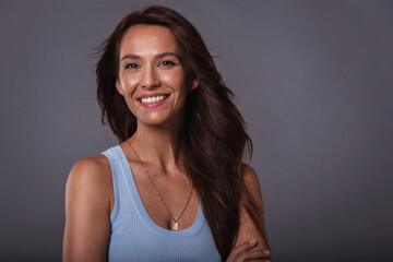 Beautiful brown haired woman studio portrait while looking at camera and smiling