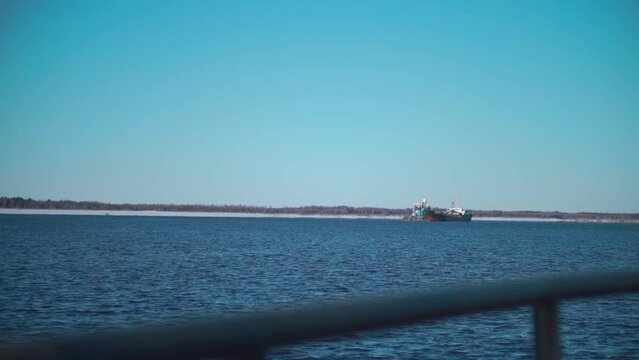 A snowy sea with ships.Clip. Huge ships with cargo move through the snowy sea, behind which the forest is visible.