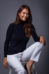Studio portrait of attractive brown haired woman with toothy smile posing at isolated grey background