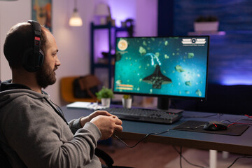Person playing video games with joystick and headset on computer. Player using controller and audio headphones for online gaming. Gamer having fun activity with equipment to play games.