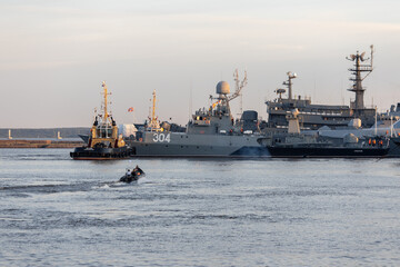 A tug and a rubber boat with sailors at the Petrovskaya pier in the city of Kronstadt against the...