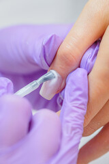 Closeup shot of woman in nail salon receiving manicure by beautician with nail file and machine. Woman getting nail manicure.